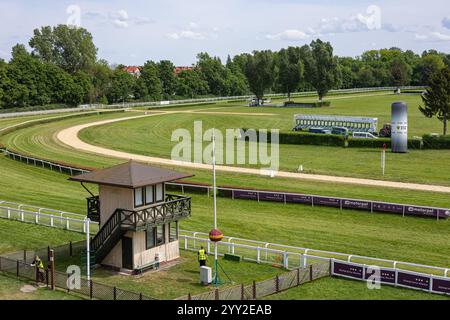 Wroclaw, Polen – 3. Mai 2024: Malerischer Blick auf die Pferderennbahn mit Starttoren, Kontrollturm und grünem Grasfeld in einem hippodrom in Breslau Stockfoto