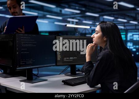 Softwareentwickler konfigurieren die Serverfarm neu, um sie für die Datenverarbeitungsanforderungen der Kunden zu optimieren. Indische Frau stellt sicher, dass Rechenzentrumsausrüstung effizient funktioniert Stockfoto