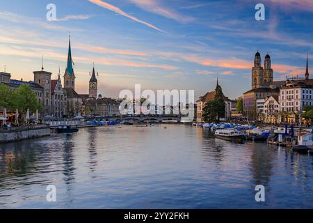 Stadtbild von Zürich, Schweiz, in der Abenddämmerung. Gebäude am Ufer der Limmat, die durch die Altstadt fließen, Boote entlang des Ufers Stockfoto