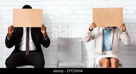 Afroamerikanische Jobbewerber schließen ihre Gesichter mit leeren Schildern im Büro des Unternehmens, Raum für Design Stockfoto