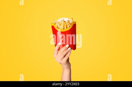 KHARKIV, UKRAINE - 4. APRIL 2020: Weibliche Hand zeigt pommes von McDonald's in roter Verpackung auf farbigem Hintergrund Stockfoto