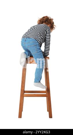 Kleiner Junge, der auf einem Hocker vor weißem Hintergrund sitzt Stockfoto