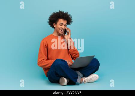 Junger afroamerikanischer Mann genießt eine zwanglose Unterhaltung, während er einen Laptop benutzt Stockfoto