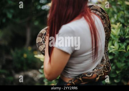 Mädchen mit langen Haaren hält draußen eine große Schlange Stockfoto