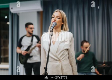 Weibliche Sängerin tritt bei einer fesselnden Musikprobe live mit der Band auf Stockfoto