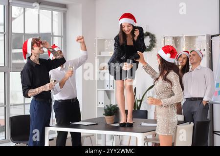Junge Kollegen mit Sekttanz auf der Neujahrsfeier im Büro Stockfoto