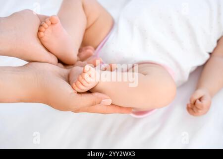 Mutter hält die Beine ihres kleinen Babys im Schlafzimmer, Nahaufnahme Stockfoto