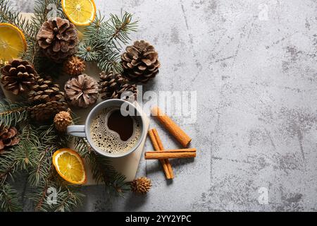 Tannenzapfen mit Tannenzweigen, Scheiben getrockneter Orange und Tasse Kaffee auf grauem Hintergrund Stockfoto