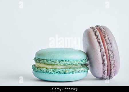 Zwei bunte französische Macarons, Kuchen mit verschiedenen Aromen, Minze, Apfel, Johannisbeergeschmack. Nachtisch, Makronen, Aquamarin, grün, lila. Spac kopieren Stockfoto