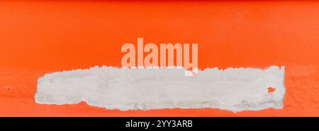 Der gesamte Rahmen der lackierten orangefarbenen Betonwand löst sich ab. Stockfoto