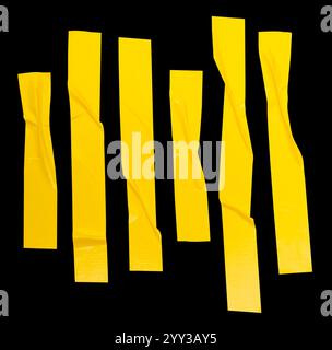 Draufsicht Set aus zerknittertem oder zerknittertem gelbem Vinyl- oder Stoffband in Streifenform ist auf schwarzem Hintergrund mit Beschneidungspfad isoliert. Stockfoto