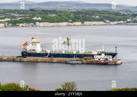 Douglas, Isle of man - 18. Mai 2023: Ein Frachtschiff im Hafen mit dem Turm der Zuflucht und den Häusern auf der Promenade im Hintergrund Stockfoto