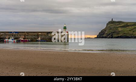 Port Erin, Rushen, Isle of man - 18. Mai 2023: Blick auf den Pier und den Leuchtturm mit den Klippen und dem Milner's Tower im Hintergrund Stockfoto