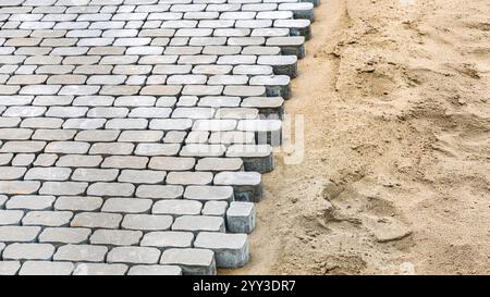 Kopfsteinpflaster auf Sandbasis, die Details von unfertigen Pflasterarbeiten zeigen. Bau- und Grundbaukonzept Stockfoto