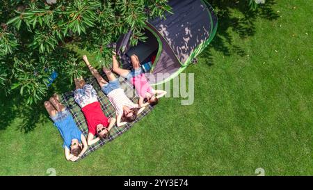 Familienurlaub auf dem Campingplatz aus der Vogelperspektive von oben, Eltern und Kinder entspannen sich und haben Spaß im Park, Zelt und Campingausrüstung unter Bäumen Stockfoto