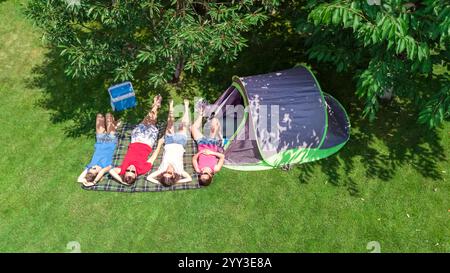 Familienurlaub auf dem Campingplatz aus der Vogelperspektive von oben, Eltern und Kinder entspannen sich und haben Spaß im Park, Zelt und Campingausrüstung unter Bäumen Stockfoto