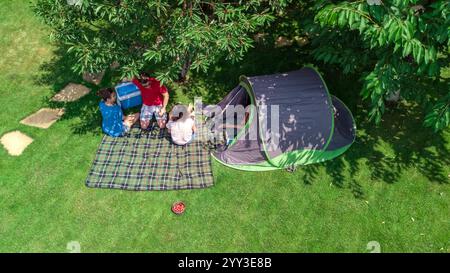 Familienurlaub auf dem Campingplatz aus der Vogelperspektive von oben, Eltern und Kinder entspannen sich und haben Spaß im Park, Zelt und Campingausrüstung unter Bäumen Stockfoto