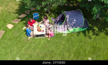 Familienurlaub auf dem Campingplatz aus der Vogelperspektive von oben, Eltern und Kinder entspannen sich und haben Spaß im Park, Zelt und Campingausrüstung unter Bäumen Stockfoto