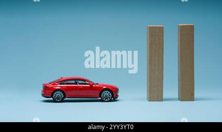 Holzblöcke vor dem roten Spielzeugauto auf blauem Hintergrund. Problem, Frustrationskonzept Stockfoto