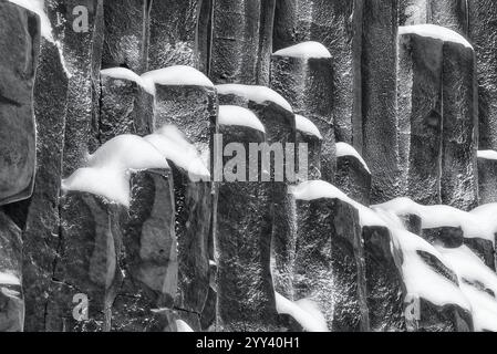 Schneebedeckte Basaltsäulen in einer Klippe, Island. Stockfoto