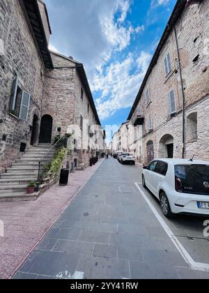 Assisi, Italien - 5. Juli 2022: Eine malerische Kopfsteinpflasterstraße, gesäumt von historischen Steinhäusern in einem europäischen Dorf. Die Szene fängt einen Frieden ein Stockfoto