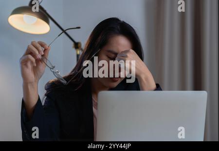 Müde junge asiatische Frau fühlt Schmerzen Augenanstrengung in der Hand Brille reiben trockene gereizte Augen müde von der Computerarbeit Stockfoto