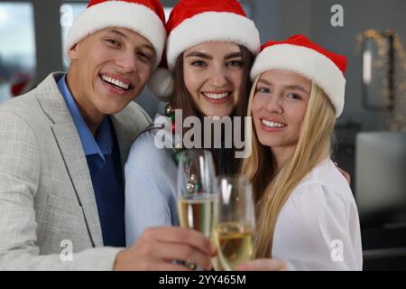 Glückliche Kollegen, die während der Weihnachtsfeier im Büro ein Glas Wein anstoßen Stockfoto