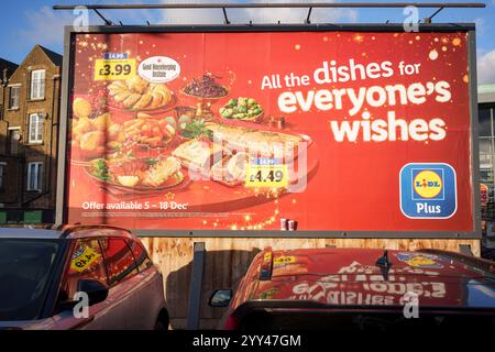 Neben einem Burger King Restaurant befindet sich am 4. Dezember 2024 in Peckham, London, England eine Plakatwand für die Lidl-Supermarktmarke, die einen Tisch voller Weihnachtsgerichte anpreist. Stockfoto