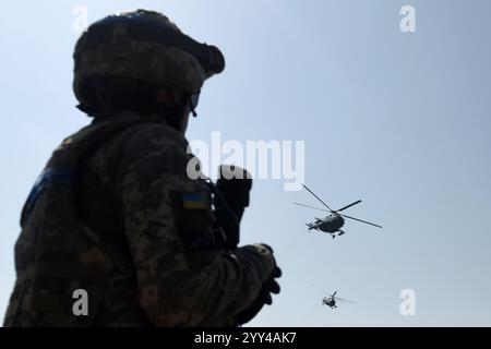 Ukrainischer Soldat sieht Militärhubschrauber, die am Himmel fliegen. Krieg in der Ukraine Stockfoto