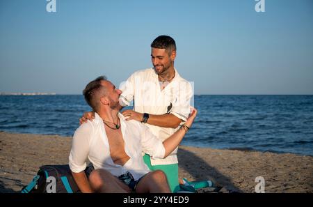 Ein fröhliches schwules Paar genießt eine schöne Zeit am Strand, symbolisiert Liebe und Vielfalt. Die ruhige Kulisse unterstreicht ihr Glück und ihre Verbindung Stockfoto