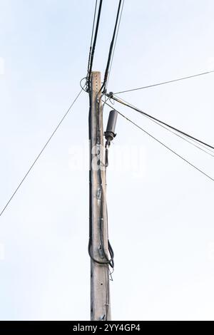 Versorgungsmasten, die in einer Outdoor-Klasse auf einem Bauernhof installiert werden und sich auf Kommunikations- oder Stromleitungen vor einem klaren Himmel konzentrieren. Stockfoto