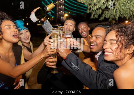 Eine Gruppe fröhlicher Freunde, die bei einer lebhaften Stadtparty mit Champagner anstoßen Lachen, Freude und festliche Vibes füllen die Nacht, während sie gemeinsam feiern Stockfoto