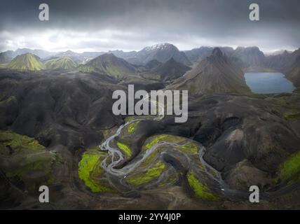 Ein atemberaubender Blick aus der Vogelperspektive auf Islands zerklüftetes Gelände fängt lebhafte Kontraste zwischen dunklen Vulkanbergen und üppig grünen Tälern ein und zeigt ungezähmte Blicke Stockfoto