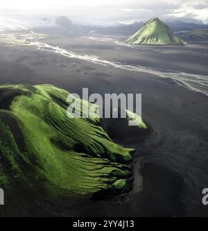 Die raue Landschaft Islands mit üppigen grünen Bergen und fließenden Flüssen aus der Vogelperspektive fängt die isolierte Schönheit und Ruhe isländischer Inseln ein Stockfoto