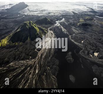 Ein atemberaubender Blick aus der Vogelperspektive auf Islands dramatisches Hochland mit leuchtenden grünen Gipfeln und zerklüfteten Tälern unter einem weiten Himmel fängt Islands un ein Stockfoto