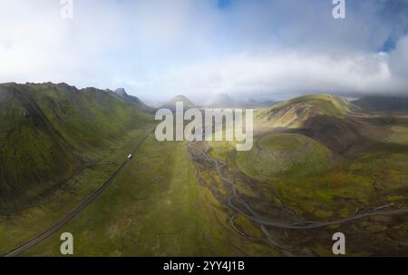 Ein atemberaubender Blick aus der Vogelperspektive auf Islands weitläufige grüne Landschaft, die die gewundenen Straßen und Bäche, umgeben von zerklüfteten Hügeln und offenem Himmel, hervorhebt Stockfoto