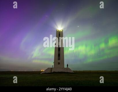 Die Nordlichter färben den Himmel in leuchtenden Grün- und Violetttönen über dem Leuchtturm von Knarraros, Eine atemberaubende Mischung aus himmlischer Schönheit und isländischem Archit Stockfoto