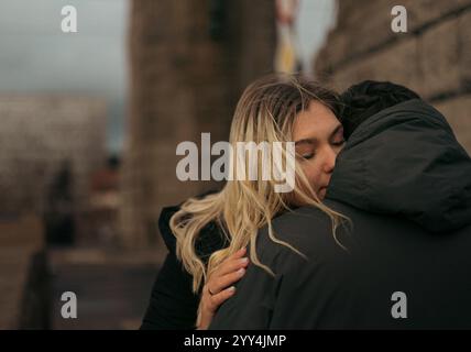 Ein junges verheiratetes Paar, ein Mann und eine Frau, teilen sich während der kühlen Jahreszeit eine zärtliche Umarmung in der historischen Stadt Breslau, Polen. Die Frau, die sucht Stockfoto