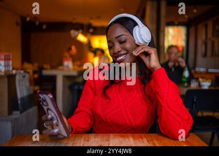 Zufriedener Kunde, der Musik mit Kopfhörern und Mobiltelefon in einem Restaurant genießt Stockfoto