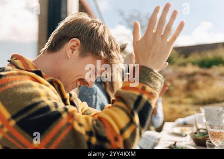 Glücklicher junger Mann, der sich an sonnigen Tagen mit Freunden versammelt Stockfoto