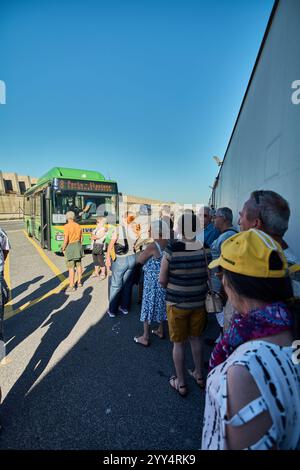 Civitavecchia. Italia - 19. Dezember 2024: Passagiere stehen an einem sonnigen Tag neben einem grünen Bus an einer Bushaltestelle und folgen der gelben Linie weiter Stockfoto