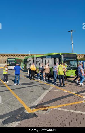 Civitavecchia, Italien - 19. Dezember 2024: Reisende mit Gepäck steigen an der gekennzeichneten Haltestelle aus, wobei das Personal in Warnwesten hilft Stockfoto