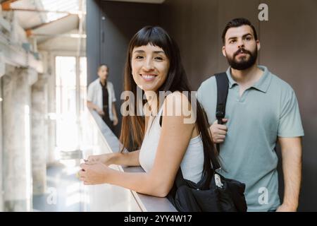 Porträt einer lächelnden Frau mit Pony, die in der Nähe der umliegenden Mauer im Universitätskorridor steht Stockfoto