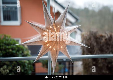 Ein leuchtendes Sternchen aus Papier hängt in einem Fenster und verleiht einem gemütlichen Zuhause einen warmen und festlichen Touch Stockfoto
