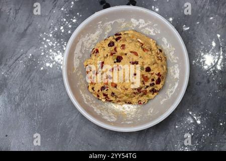 Nahaufnahme eines zuckerfreien Teigs in einer Schüssel. Zubereitung von Teig für Kekse mit Rosinen und Preiselbeeren, essengesundes Konzept. Stockfoto