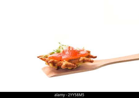 Gemüskartoffelwaffeln mit Aufstrich und leicht gesalzenem rotem Fisch auf einem Spachtel, isoliert auf weißem Hintergrund Stockfoto