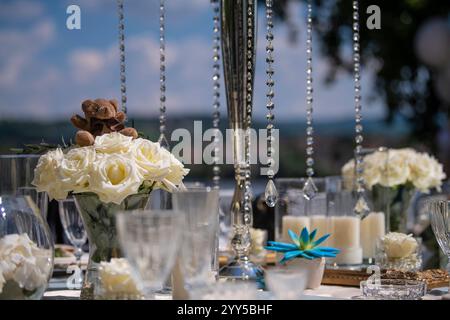 Detailansicht der wunderschönen Tischdekoration für Hochzeiten oder Geburtstagsfeiern. Bankett. Dekoration mit Kristallen, Kerzen, Blumen, Servietten und einem Teddybären. Stockfoto