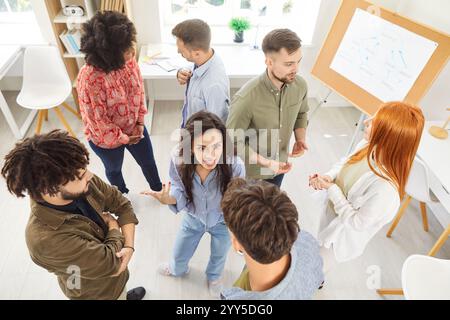 Gruppe von Mitarbeitern des Unternehmens, die im Büro stehen, Strategien besprechen und während des Meetings Ideen austauschen. Stockfoto