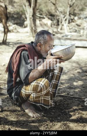 Ali trinkt Milch nach dem Melken eines seiner Kamele (Camelus dromedarius), Kamelfarm von Scheich Ahmed Ali Al-Mahri, Sarfeit, Dhofar, Oman, Asien Stockfoto