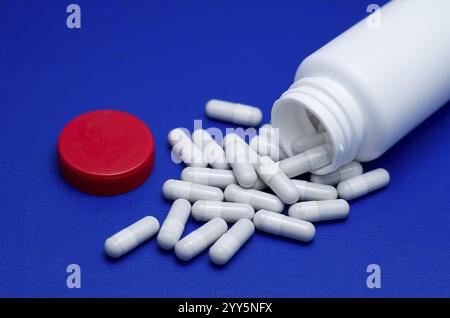 Große weiße Pillen fielen aus einer großen weißen Flasche. Leben ohne Drogen und Abhängigkeit von Kapseln mit Antibiotika, Medizin, Amphetaminen, Medikamenten und Medikamenten Stockfoto